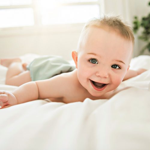 A cute baby boy lying on a white bed