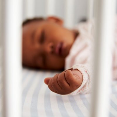 Close Up Of Baby Girl Sleeping In Nursery Cot