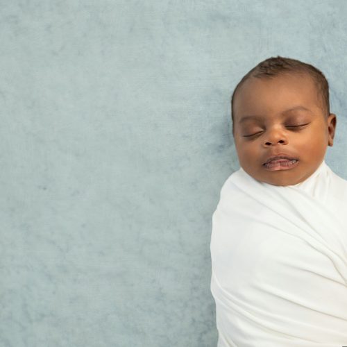 swaddled African-American baby boy sleeping on a rug